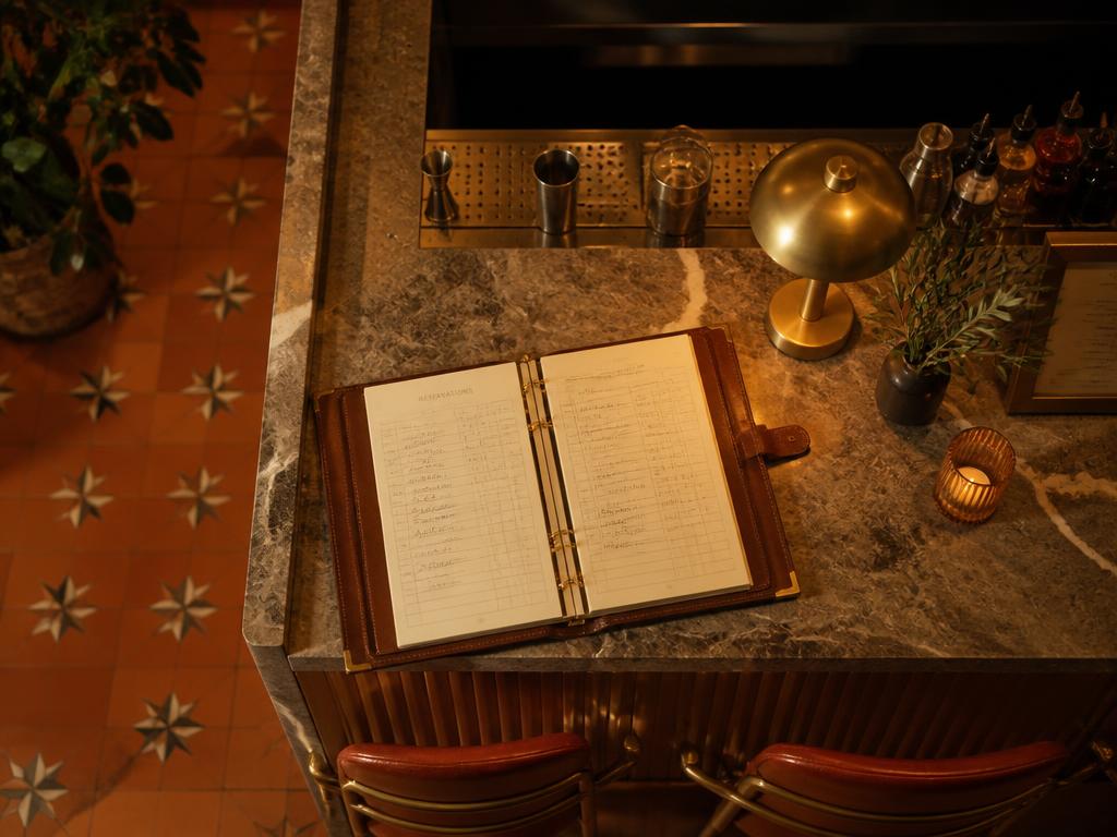 Leather reservation ledger open on a marble bar top with brass fittings